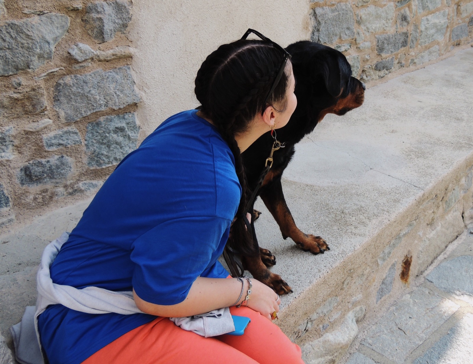 Ragazza seduta su un gradino accanto al suo Rottweiler, tranquilli uno di fianco all'altra